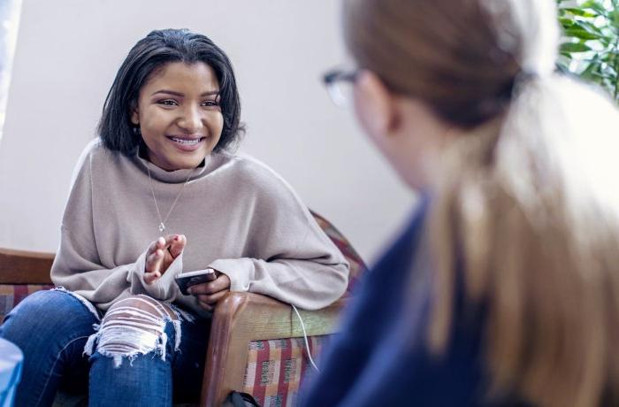 A student sits in a chair talking to someone.